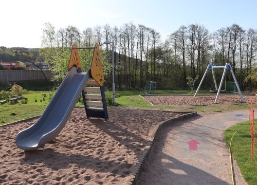 Rutschkana i sandlåda med kompisgunga i bakgrunden