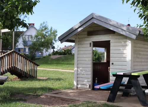 Vit lekstuga, träbänkar och träbro