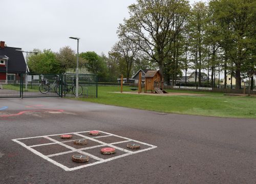 Tre-i-rad på asfalt, gräsplan och klätterställning i bakgrunden