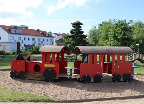 Rött trätåg – gräsplan och träd i bakgrunden