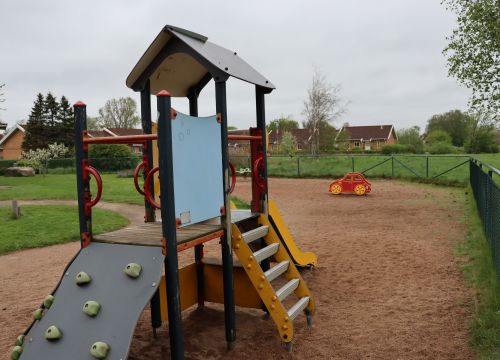 Klätterställning med röd gungbil i bakgrunden