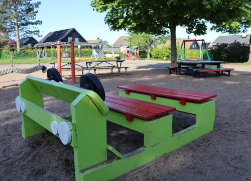 Grön leksaksbil med gården i bakgrunden