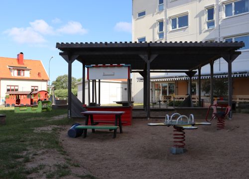 Sandlåda med gungleksaker, solskydd och bänkar