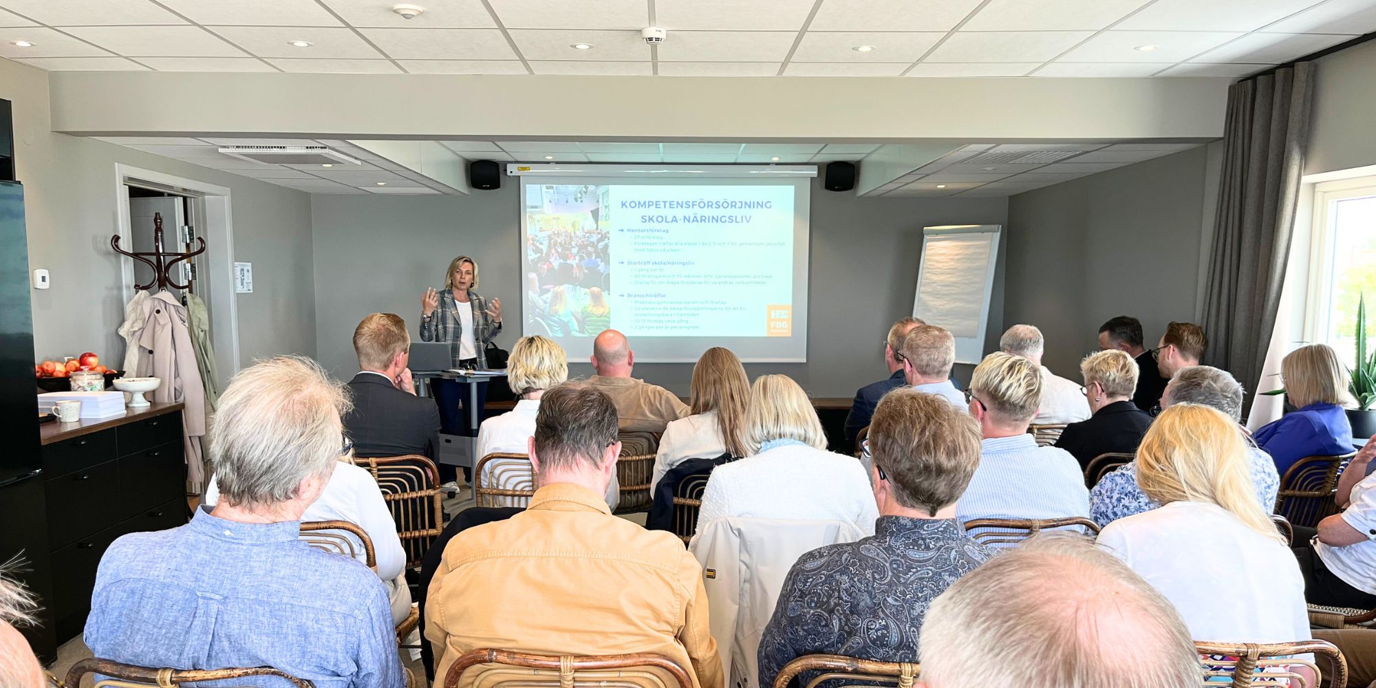 Emma Carlström står längst fram i en lokal och håller en dragning framför en publik.