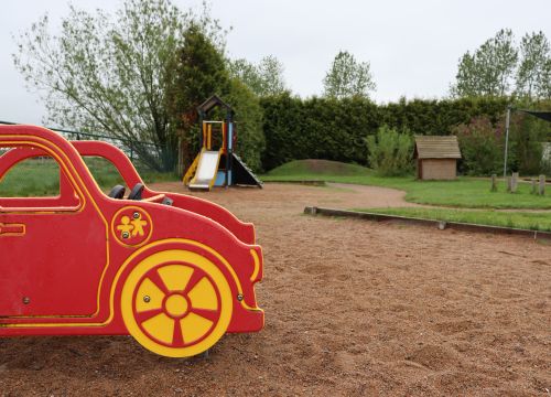 Röd gungbil med gården i bakgrunden