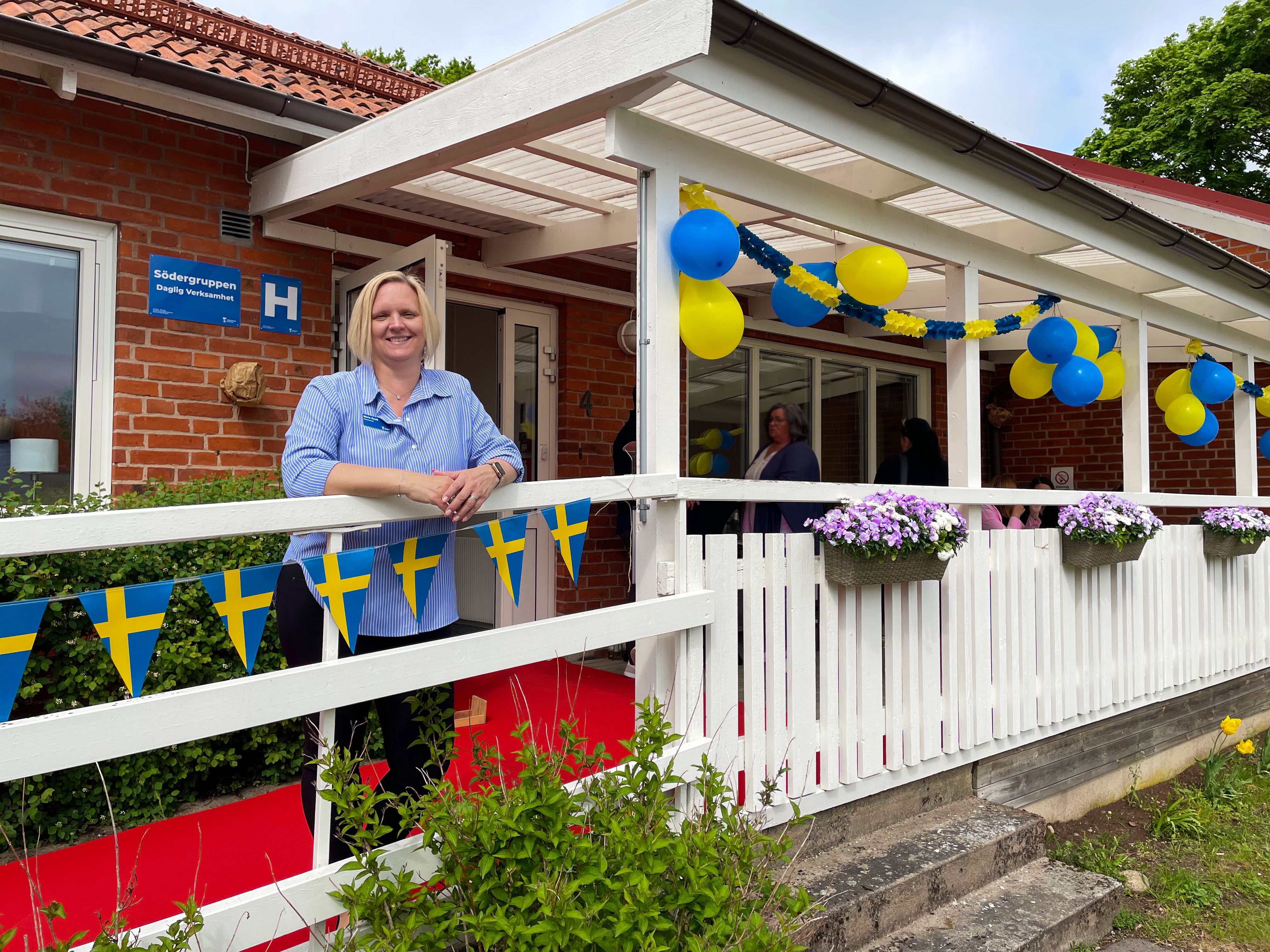 Marie Scott står framför entrén till Södergruppen. Det är pyntat med blågula ballonger och svenska flaggor.