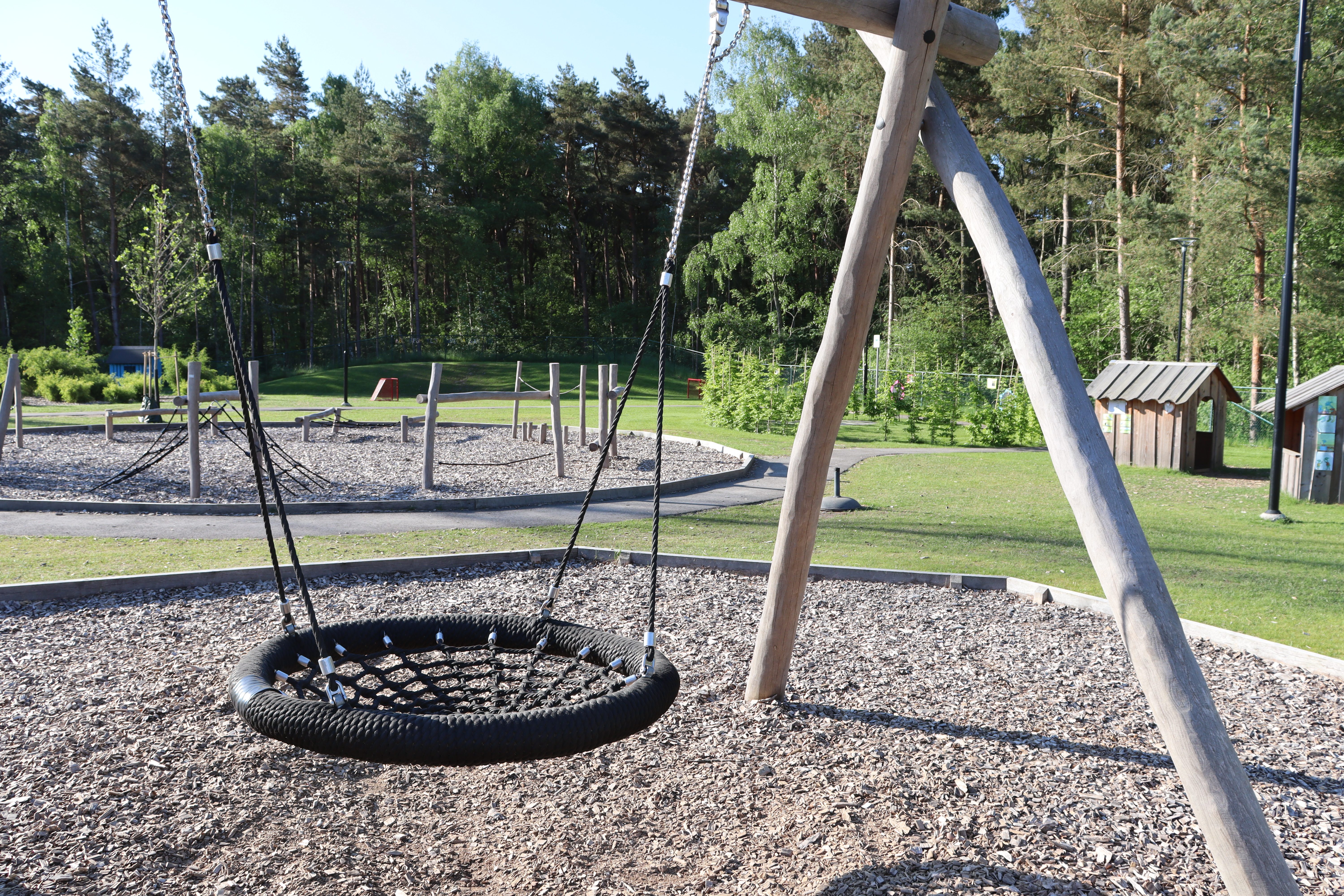 Kompisgunga med balansbana och lekstugor i grön bakgrund