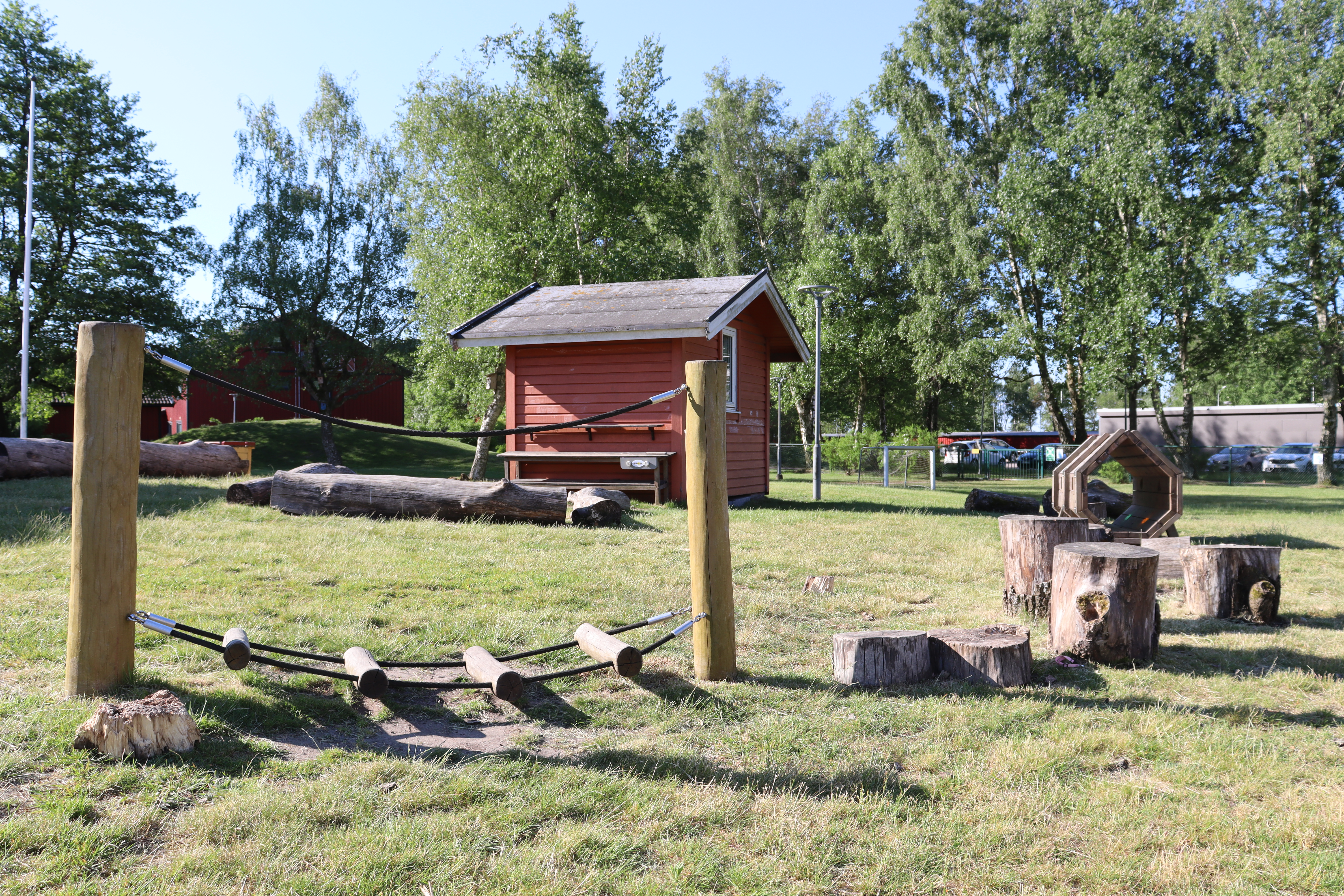 Balansbana på gräs med röd stuga i bakgrunden