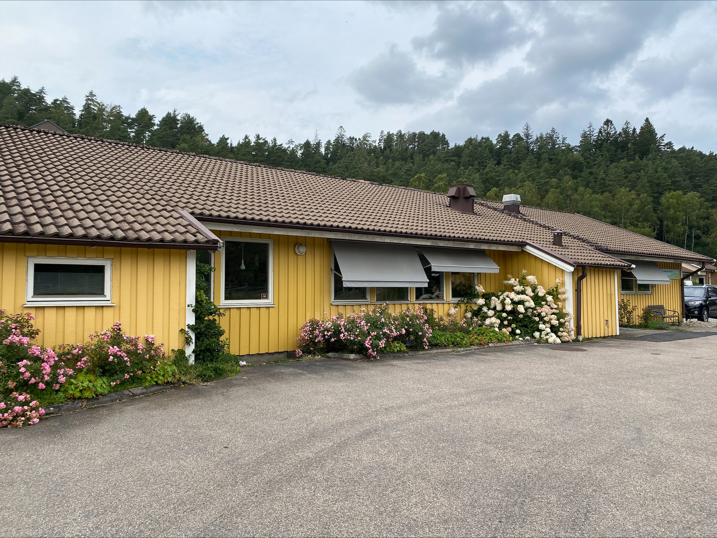 Låg gul tegelbyggnad med grön leksaksbuss i förgrunden