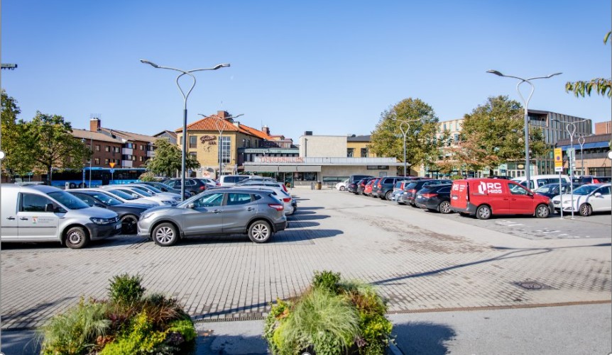 Stortorget i Falkenberg med blå himmel och många bilar parkerade.