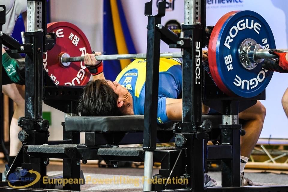 Carl på rygg på bänk och lyfter skivstång.