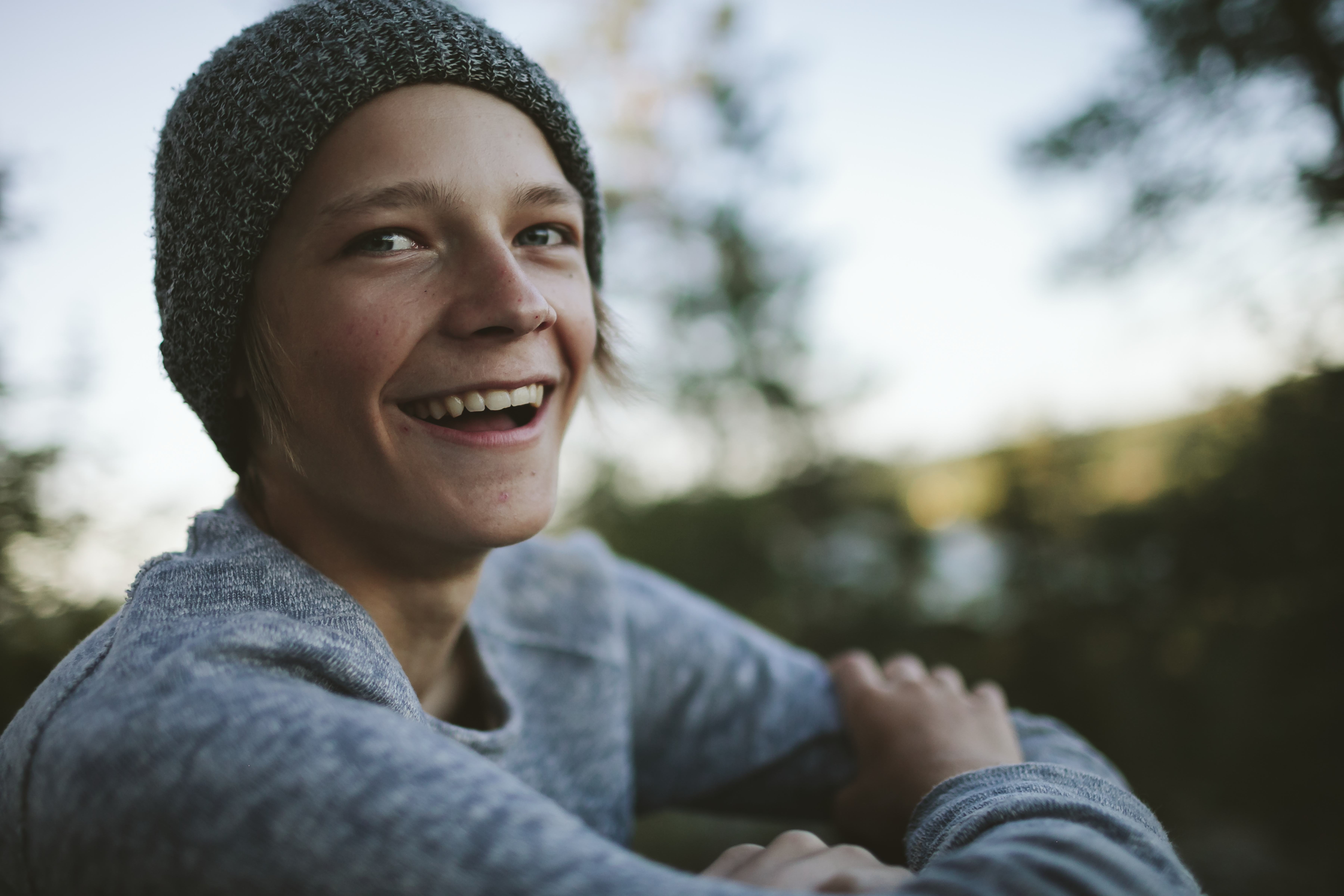 Tonårskille med mössa ler och tittar in i kamera.