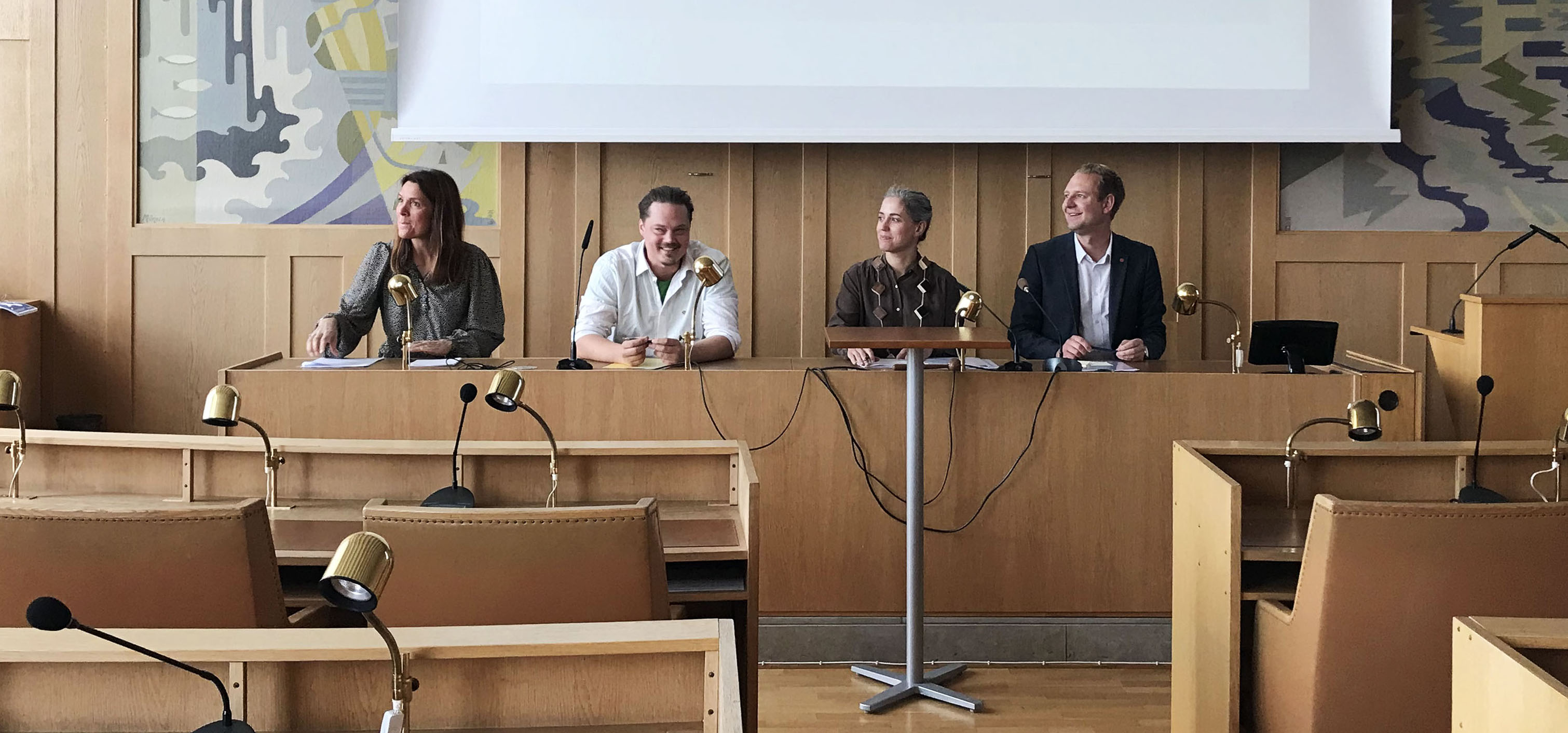 Representanter från de fyra partierna i Framtid Falkenberg sitter i kommunfullmäktigesalen i Stadshuset. Från vänster: Petra Hygrell (L), Markus Jöngren (MP). Georgia Ferris (KD) och Per Svensson (S).