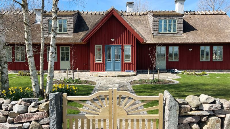 Byggnaden i sin helhet – brun och lång och mycket grönt gräs.