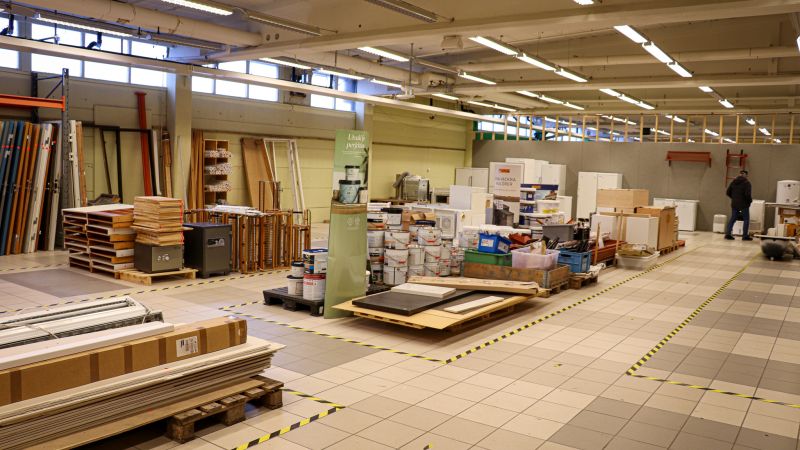Öppen lokal med gipsskivor, målarburkar, dörrar och annat byggmaterial.