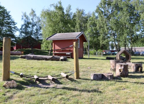 Balansbana på gräs med röd stuga i bakgrunden