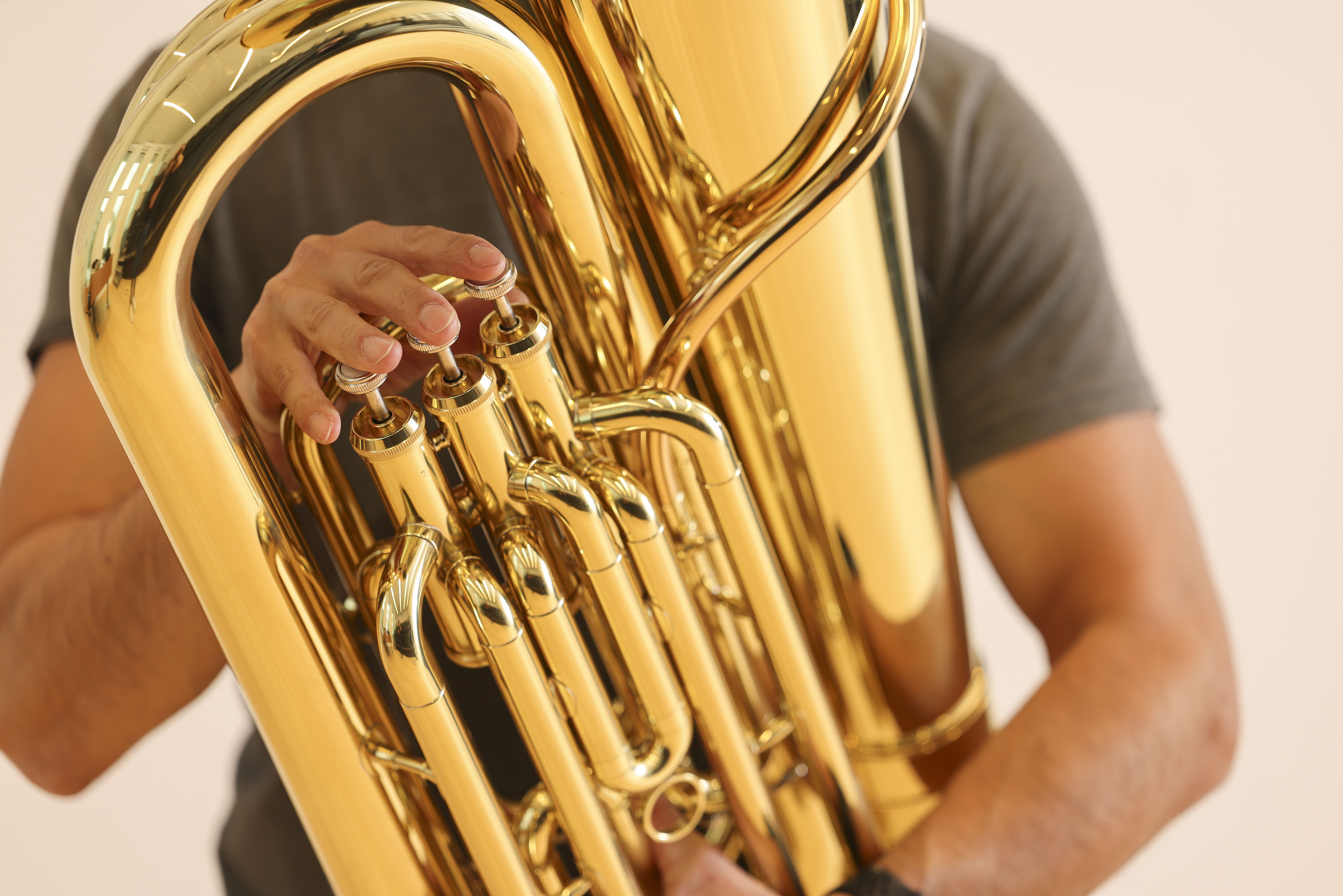 Närbild på ett brassinstrument och händer som spelar