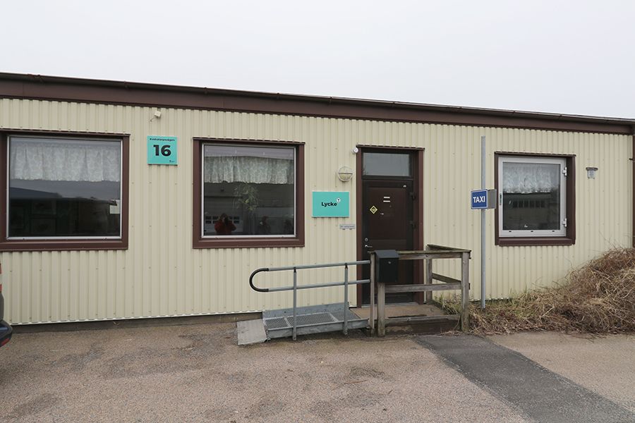 Entrén till låg, beige byggnad med bruna knutar.