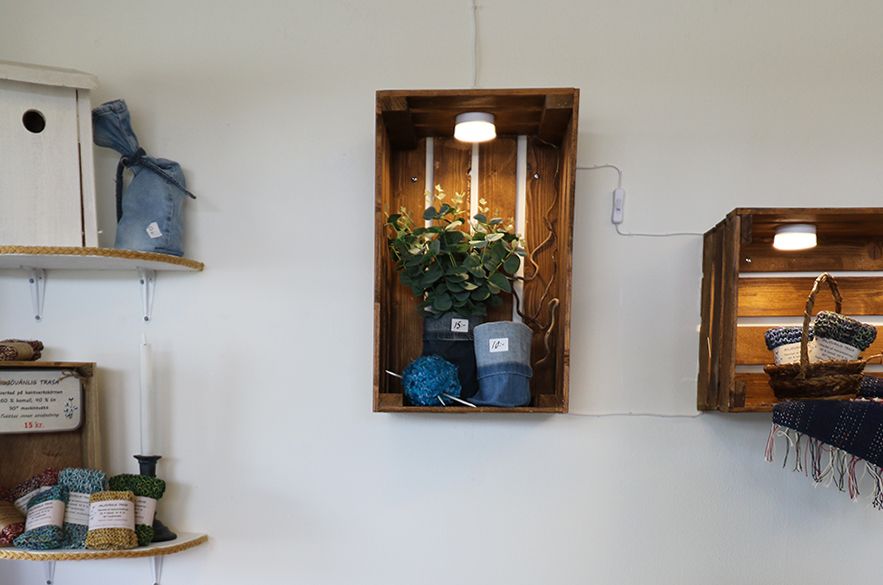 Äppellådor uppsatta på väggen. I dem står olika hantverk.