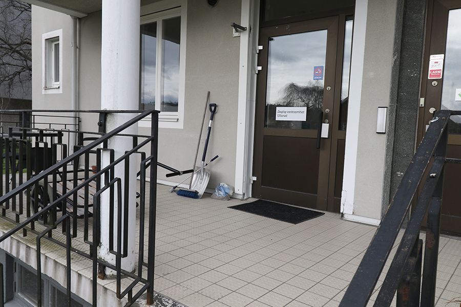 Entrén till en grå byggnad med putsad fasad. 