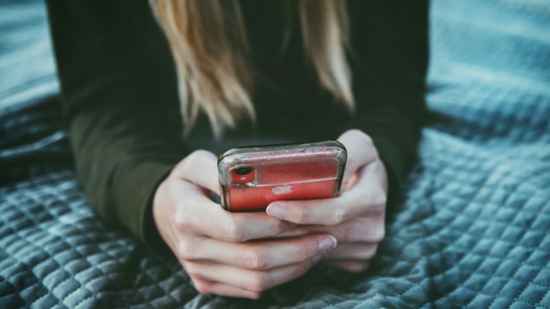 Person som håller i mobiltelefon. Telefonen i fokus.