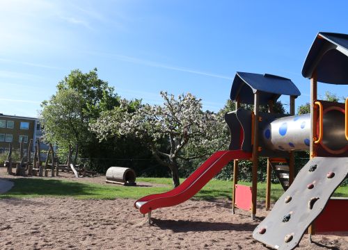 Klätterställning med rutschkana - fruktträd i bakgrunden