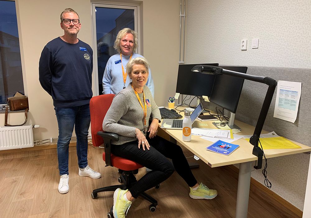 Tre personer, en man och två kvinnor, runt ett skrivbord.
