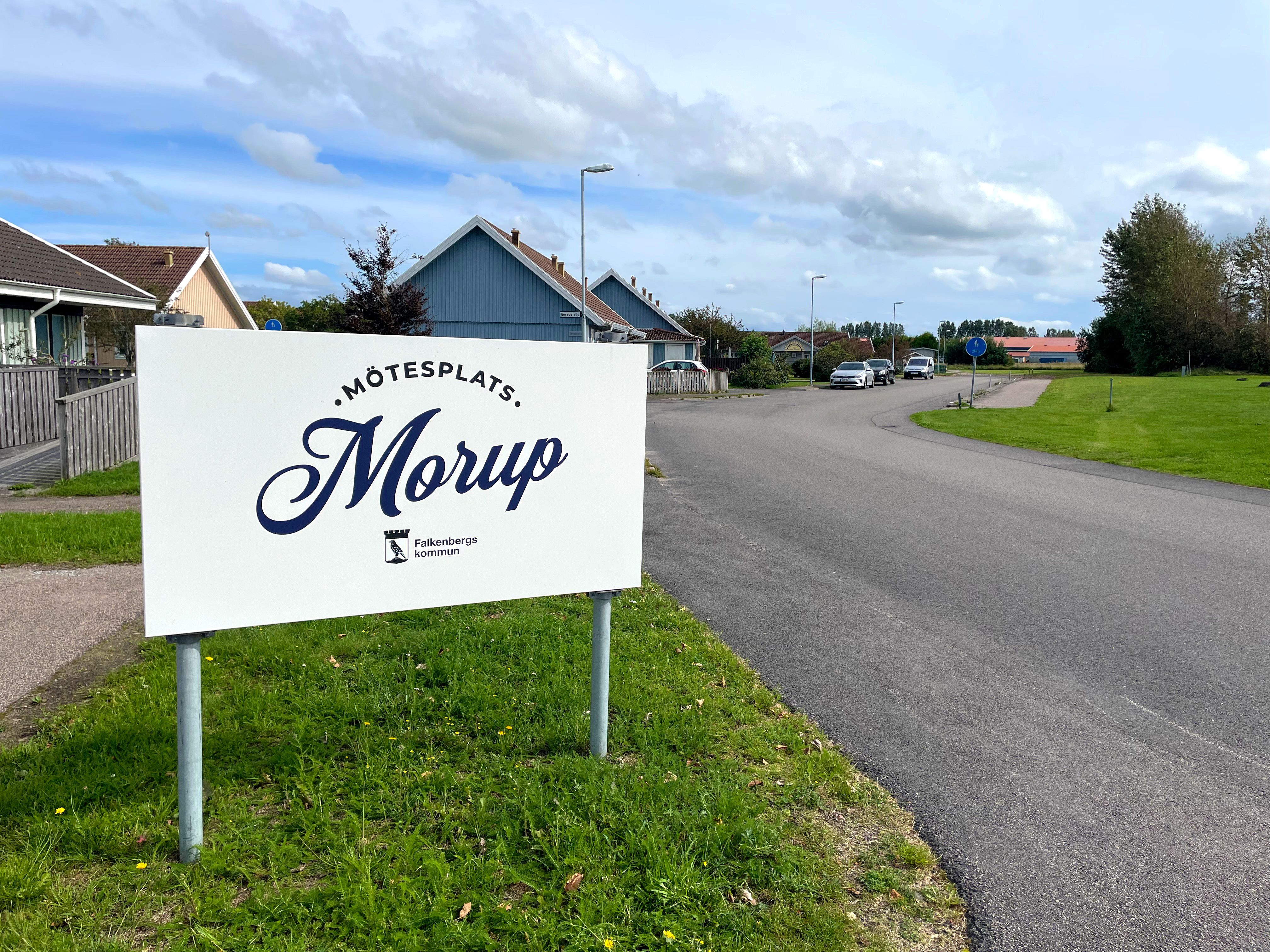Mötesplats Morups skylt. I bakgrunden syns en väg, grönt gräs och himmel.