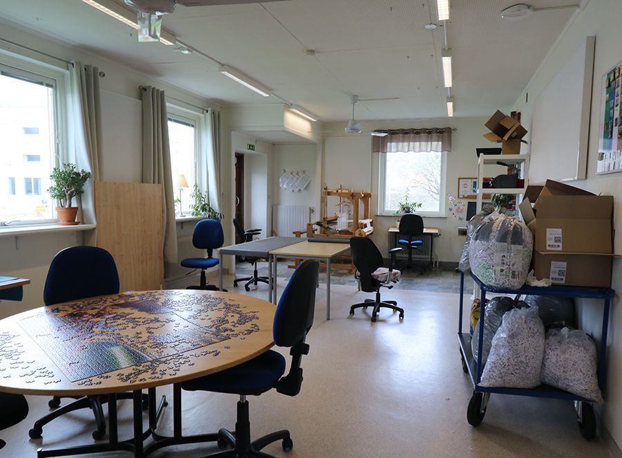 Rum med olika arbetsstationer. På ett runt bord ligger det ett stort ofärdigt pussel.