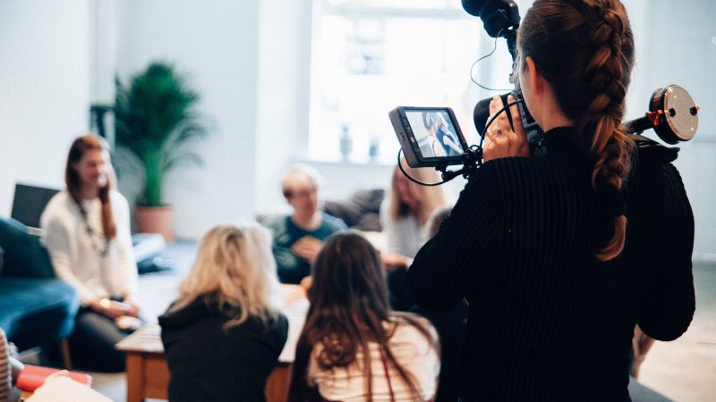 Person filmar en grupp med människor. Filmkameran är i fokus.