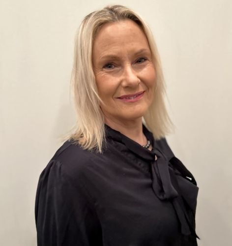 En porträttbild där hon ler. Hon har mörkblå knytblus.