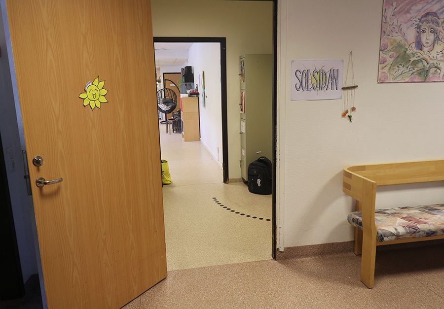 Ingång till en lokal. Utanför ingången står en träsoffa.