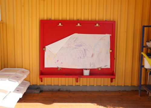 Sandlåda med klätterställning och rutschkana, gräsplan i förgrunden