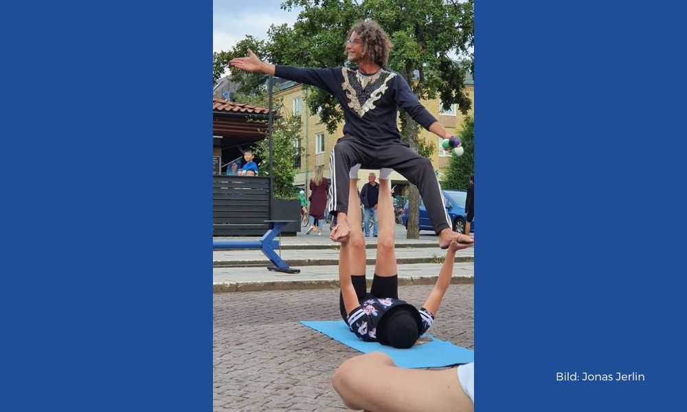 Magnus uppträder på torg, sitter på an persons fötter- med sina egna fötter på personens händer. Fotograf: Jonas Jerlin.
