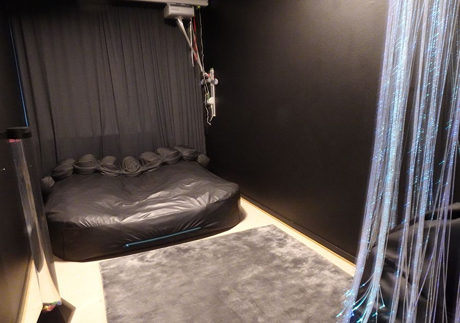 Svartmålat rum med en svart madrass och grå matta.