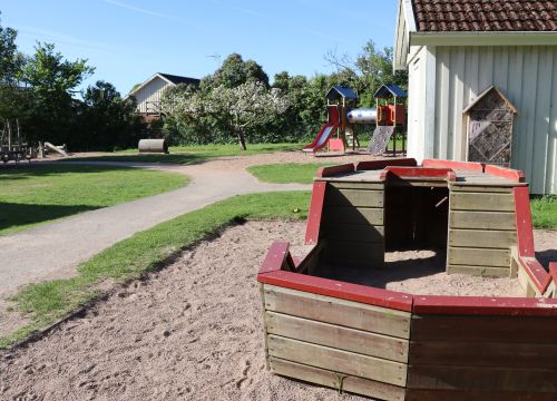 Träbåt i sant - gården i med asfaltsgångar bakgrunden