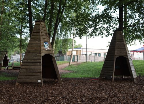 Två större trähyddor i utkanten av naturgården