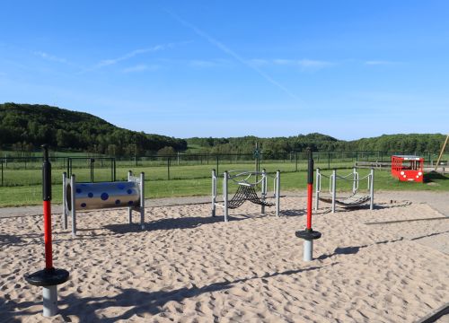 Balansbana, snurrleksaker - gräsplan och skog i bakgrunden