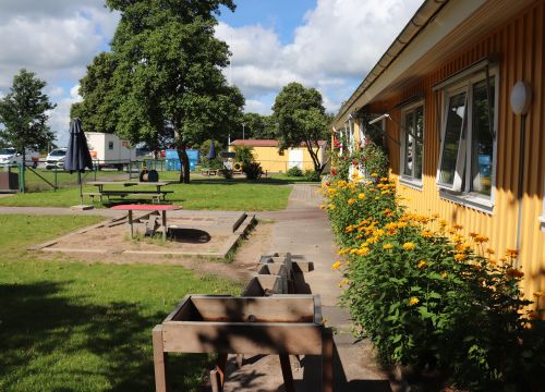 Sandlåda med klätterställning och rutschkana, gräsplan i förgrunden