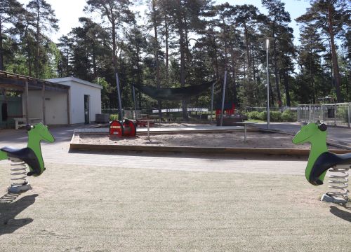 Gröna gunghästar på fjädrar, sandlåda i bakgrunden