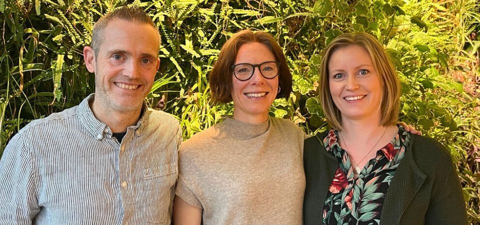 Niklas Grip, delägare och projektledare, Karin Fornell, vd och Erica Hörteborn, arkitekt och hållbarhetssamordnare står framför en grön vägg med växter.