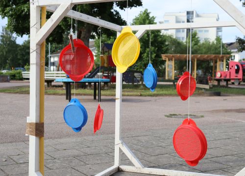 Färgglada silar som hänger i en ställning, gård i bakgrunden