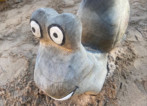 Sandlåda med solskydd – gräsplan, träd och buskar i bakgrunden