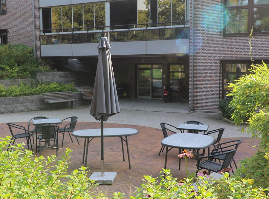 Uteplats med bord, stolar och ett parasoll.