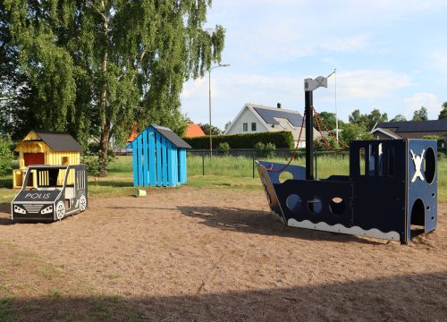 Sandlåda med blå träbåt, träpolisbil och lekstugor