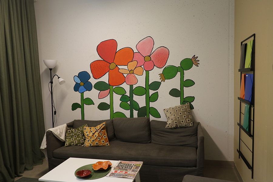 Rum med soffa. På väggen är det stora, målade blommor i olika färger.