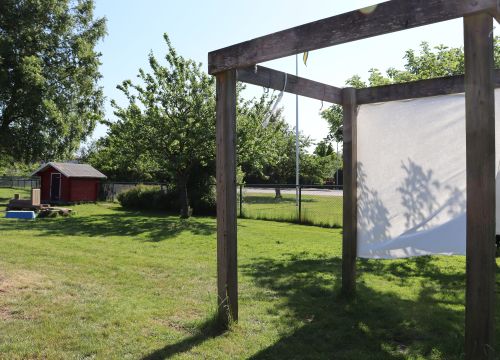 Träställning med vita skynken - grön gård med leksaker i bakgrunden