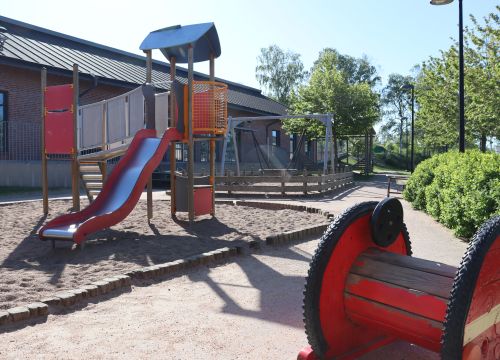 Klätterställning med rutschkana i sand - röd träspole i förgrunden