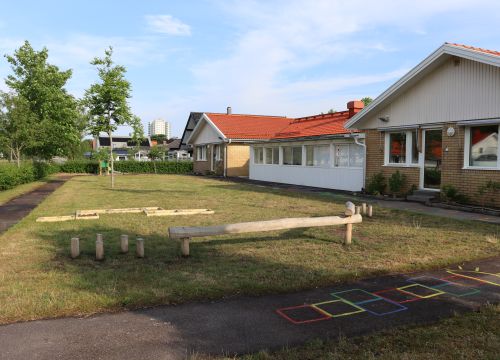 Gräsmatta med balansbana och färgglad hage på asfaltsgång
