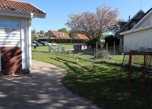 Gräsplätt med fotbollsmål och balansbana, samt asfalterad gång